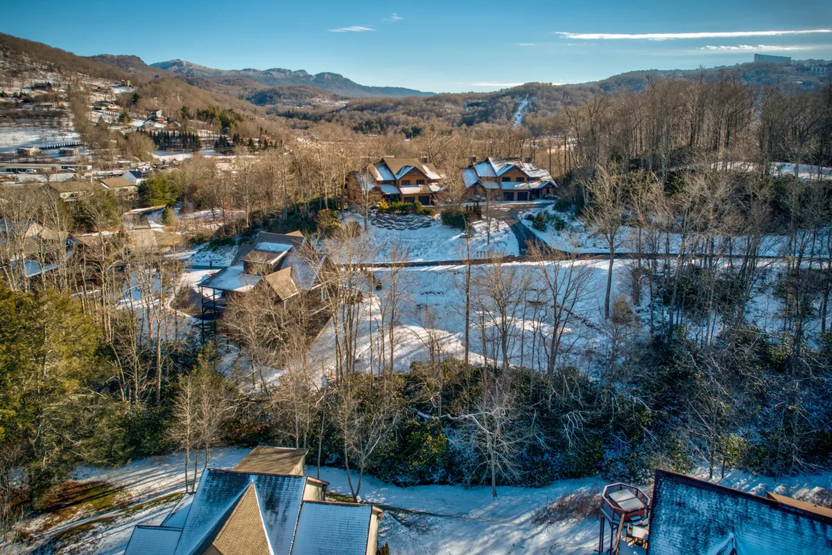 A tranquil winter scene showing wooden cabins nestled in a snow-covered landscape, with a tree line in the background. The setting evokes the quiet beauty and adventure of the snowy season, inviting thoughts of skiing, snowboarding, or cozy evenings by the fire.