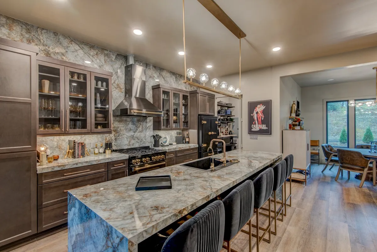 Bright, modern kitchen with a large island, top-tier appliances, and decorative lighting, seamlessly connected to the living area. Ample space for group cooking and entertaining is evident.